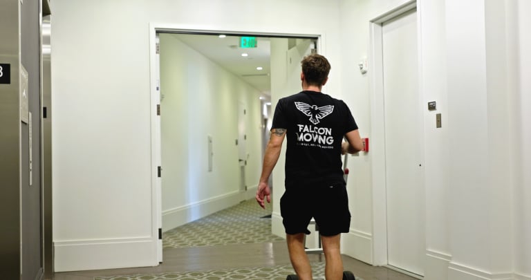 Falcon Moving mover walking a dolly down an apartment building hallway